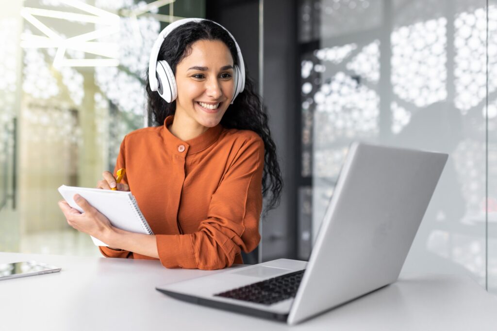 Latin american business woman with curly hair and headphones watching online training course at
